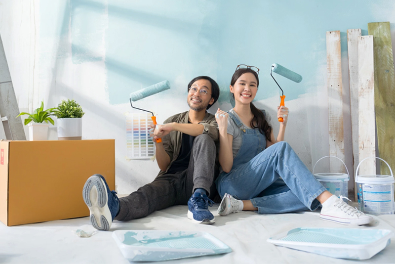 Young couple with paint rollers painting living room
